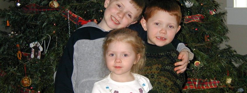 Photo of my 3 kids in front of a Christmas tree when they were little
